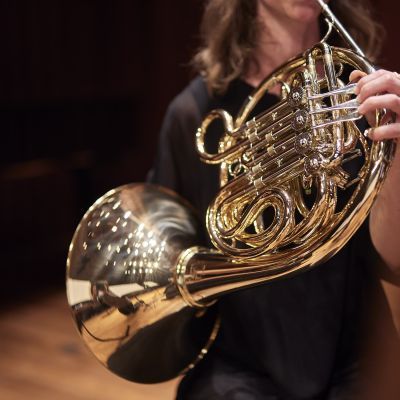 Student on stage playing French horn